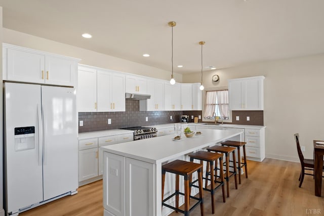 1268 Stoney Ridge Blvd, Forest, VA 24551 - kitchen featuring white refrigerator with ice dispenser, stainless steel electric range oven, under cabinet range hood, a center island, and white cabinets