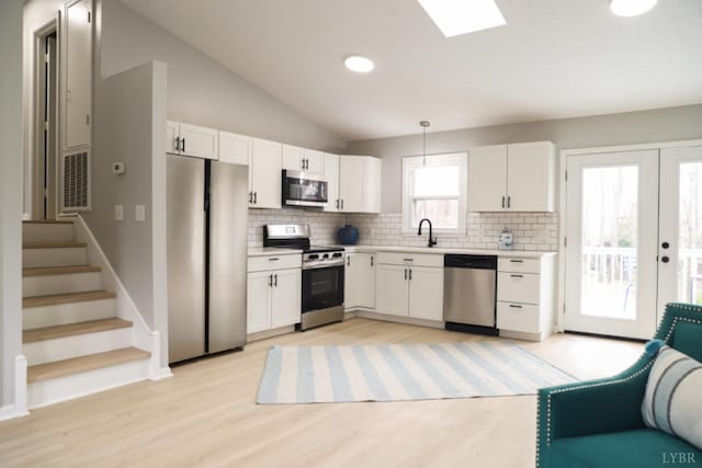 2824 Hawkins Mill Rd, Lynchburg, VA 24503 - kitchen featuring appliances with stainless steel finishes, backsplash, white cabinetry, light countertops, and light wood-type flooring