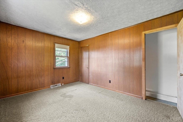 1104 Amherst Ave, Altavista, VA 24517 - spare room with a textured ceiling, carpet flooring, and wooden walls