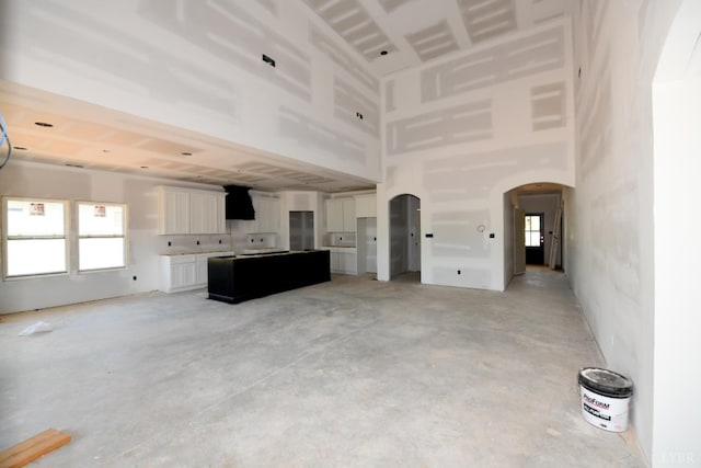 24 Stony Ridge Blvd, Forest, VA 24551 - unfurnished living room with arched walkways, a high ceiling, unfinished concrete floors, and healthy amount of natural light