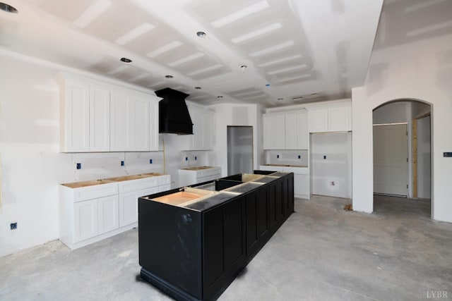 24 Stony Ridge Blvd, Forest, VA 24551 - kitchen with arched walkways, a center island, concrete floors, wall chimney range hood, and dark cabinetry