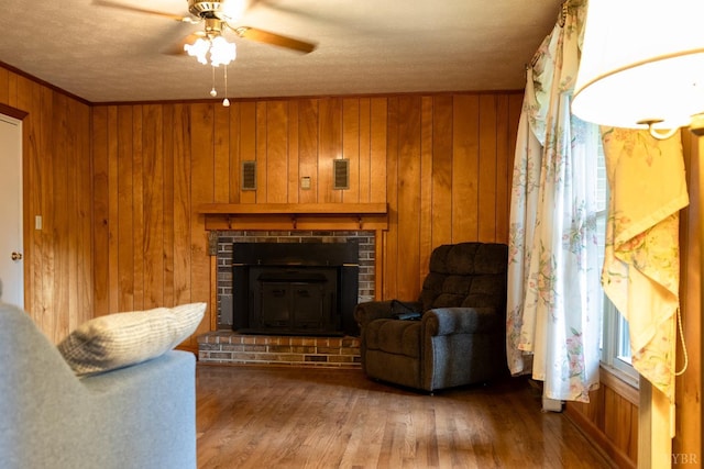 20586 Kings Hwy, Randolph, VA 23962 - living area with a ceiling fan, a brick fireplace, wooden walls, wood finished floors, and a textured ceiling
