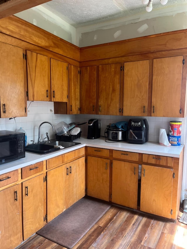 1115 Jackson St, Lynchburg, VA 24504 - kitchen featuring black microwave, a sink, light countertops, tasteful backsplash, and brown cabinetry