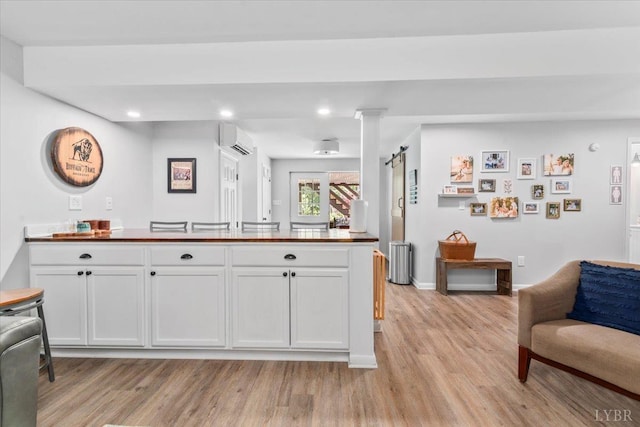 261 Carrington Ln, Roseland, VA 22967 - kitchen with radiator, light wood-type flooring, an AC wall unit, recessed lighting, and white cabinets