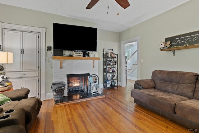221 Castle Craig Dr, Evington, VA 24550 - living room featuring a ceiling fan, a brick fireplace, wood finished floors, stairway, and baseboards
