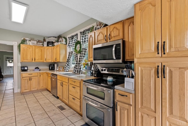 221 Castle Craig Dr, Evington, VA 24550 - kitchen with stainless steel appliances, a sink, light tile patterned floors, light countertops, and light brown cabinets