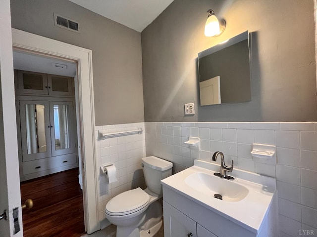 2910 Rivermont Ave Unit 301, Lynchburg, VA 24503 - half bathroom featuring tile walls, toilet, vanity, a wainscoted wall, and wood finished floors