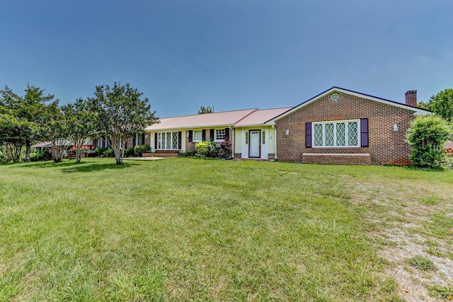 ranch-style home with a chimney, a front lawn, brick siding, and a metal roof
