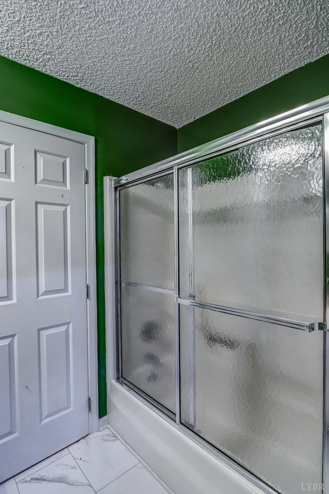 bathroom with enclosed tub / shower combo, marble finish flooring, and a textured ceiling