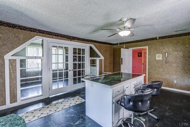 kitchen featuring french doors, wallpapered walls, a ceiling fan, a textured ceiling, and white cabinets