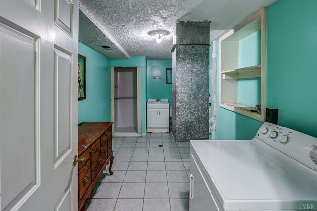 laundry area featuring washer / clothes dryer, light tile patterned floors, and a textured ceiling