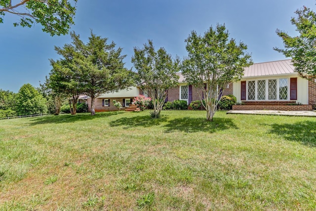 view of front of home featuring brick siding, a front lawn, and a metal roof