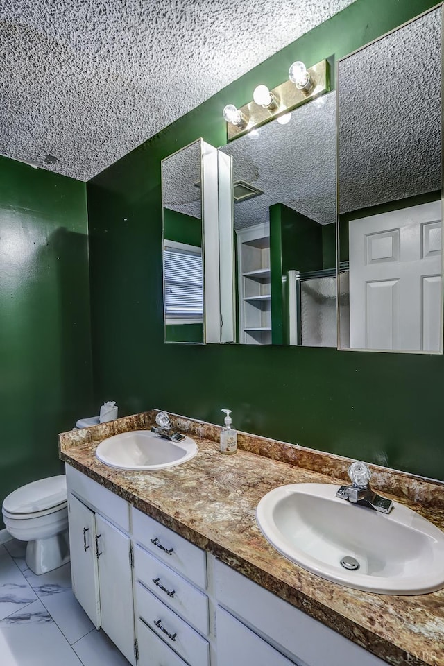 bathroom featuring double vanity, an enclosed shower, marble finish floors, and a textured ceiling