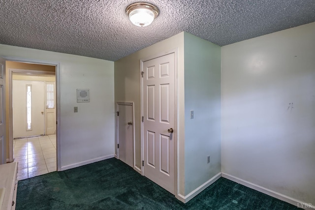 unfurnished room featuring a textured ceiling, carpet, and tile patterned floors
