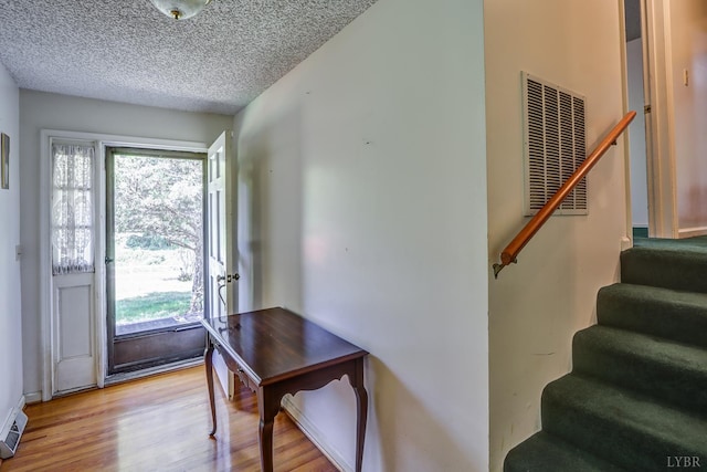 entrance foyer featuring stairway, light wood finished floors, plenty of natural light, and a textured ceiling