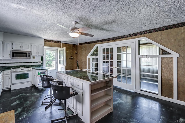 kitchen featuring stainless steel microwave, white range oven, open shelves, white cabinets, and a ceiling fan