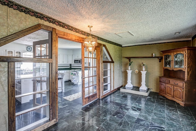 unfurnished dining area with a textured ceiling, brick wall, and a chandelier