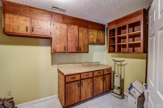 kitchen with brown cabinets, light countertops, a textured ceiling, and light tile patterned floors