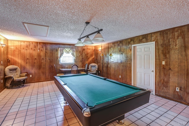 game room featuring wood walls, a textured ceiling, light tile patterned floors, and pool table