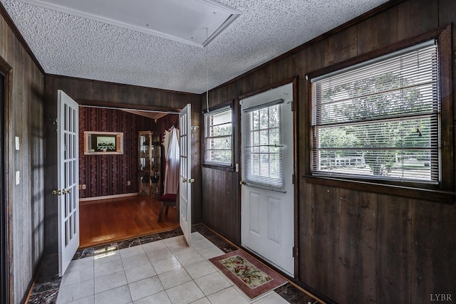 entrance foyer featuring a textured ceiling, light tile patterned flooring, and wood walls