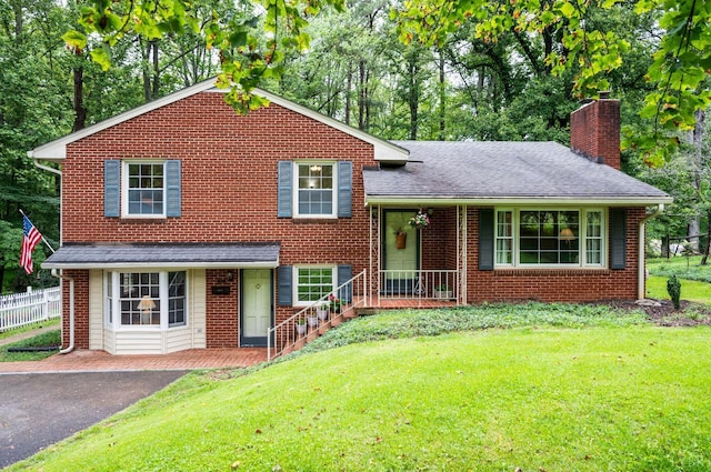 921 Peaksview St, Bedford, VA 24523 - split level home with a chimney, brick siding, roof with shingles, covered porch, and view of wooded area
