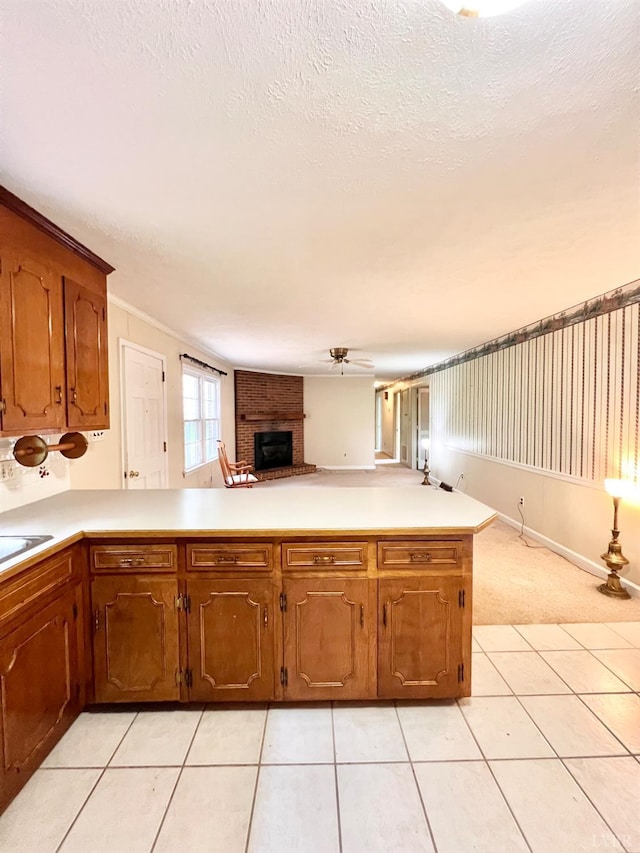 166 Matohe Rd, Monroe, VA 24574 - kitchen with a brick fireplace, open floor plan, light countertops, a peninsula, and brown cabinetry