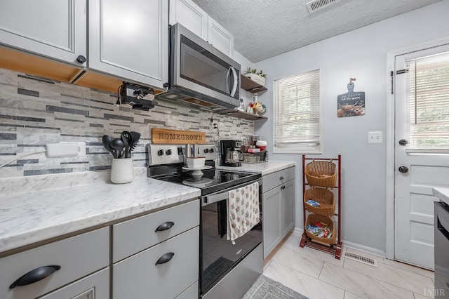 2523 Clarks Rd, Rustburg, VA 24588 - kitchen featuring appliances with stainless steel finishes, decorative backsplash, light stone countertops, gray cabinets, and a textured ceiling