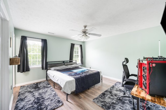 1053 Hupps Hill Ln, Forest, VA 24551 - bedroom with multiple windows, a textured ceiling, wood finished floors, baseboards, and a ceiling fan