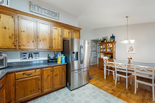 343 Soybean Dr, Appomattox, VA 24522 - kitchen with stainless steel fridge, brown cabinets, a chandelier, dark countertops, and decorative light fixtures