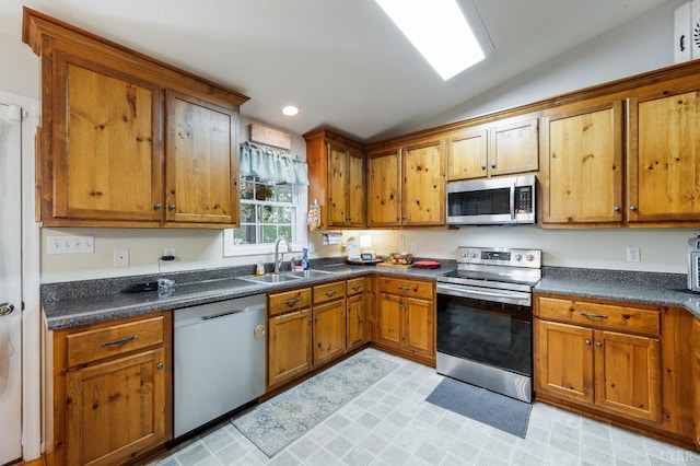343 Soybean Dr, Appomattox, VA 24522 - kitchen with appliances with stainless steel finishes, a sink, brown cabinetry, vaulted ceiling, and dark countertops