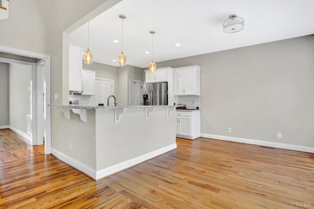 238 Ridgeline Dr, Concord, VA 24538 - kitchen with stainless steel fridge, a breakfast bar area, decorative backsplash, a peninsula, and light wood-style flooring