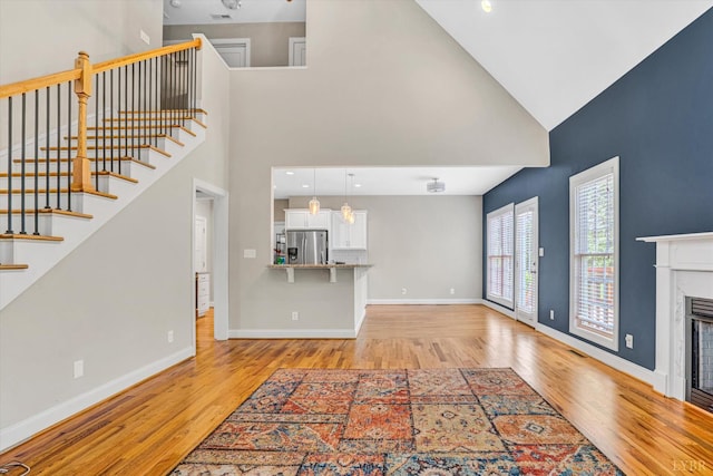 238 Ridgeline Dr, Concord, VA 24538 - unfurnished living room with high vaulted ceiling, light wood-type flooring, a fireplace, baseboards, and stairway