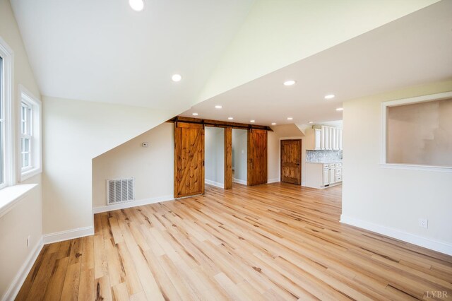 7845 Bear Creek Rd, Gladys, VA 24554 - unfurnished living room with light wood-style flooring, a barn door, recessed lighting, and vaulted ceiling