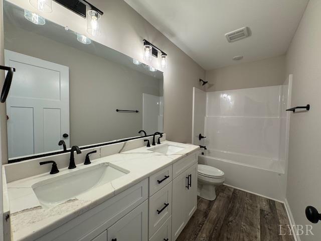 2304 Spring Grove Rd, Spout Spring, VA 24593 - full bath featuring wood finished floors, toilet, double vanity, bathing tub / shower combination, and baseboards