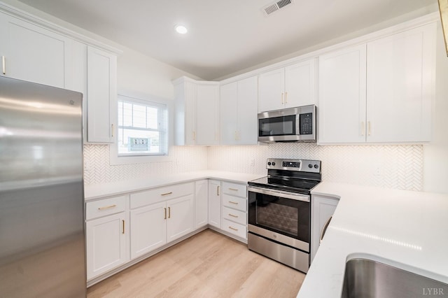 556 Leesville Rd Unit 907, Lynchburg, VA 24502 - kitchen with appliances with stainless steel finishes, light countertops, white cabinetry, light wood-type flooring, and backsplash