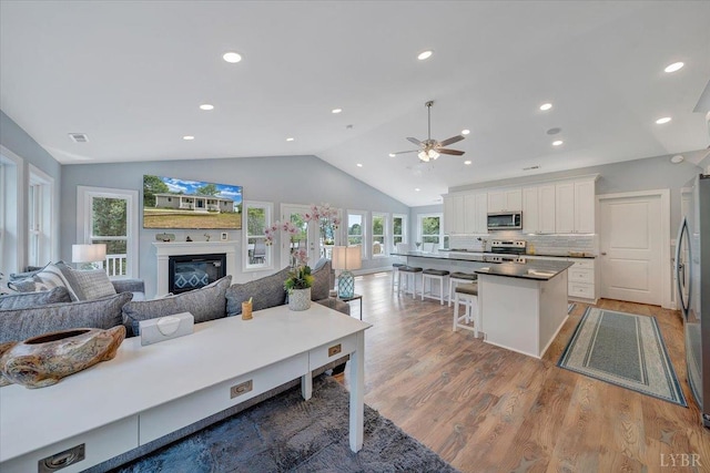 1620 Stripers Cove Rd, Goodview, VA 24095 - living area featuring a ceiling fan, lofted ceiling, wood finished floors, a glass covered fireplace, and recessed lighting