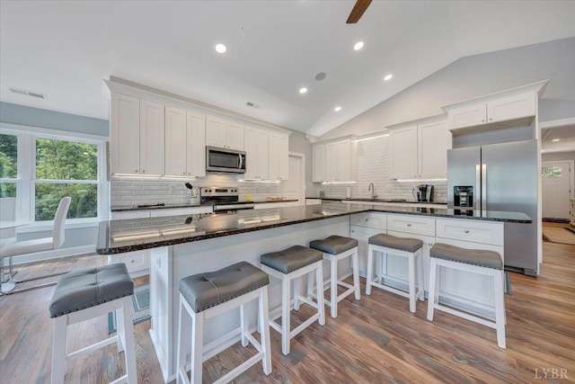 1620 Stripers Cove Rd, Goodview, VA 24095 - kitchen with appliances with stainless steel finishes, vaulted ceiling, decorative backsplash, wood finished floors, and white cabinets
