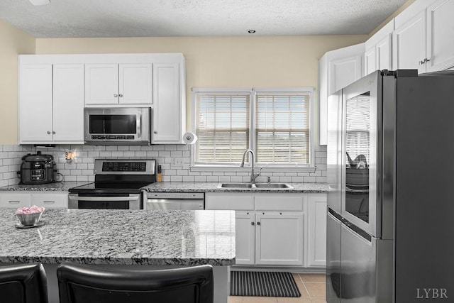 4710 Hummingbird Ln, Concord, VA 24538 - kitchen featuring appliances with stainless steel finishes, a sink, white cabinetry, tasteful backsplash, and a textured ceiling