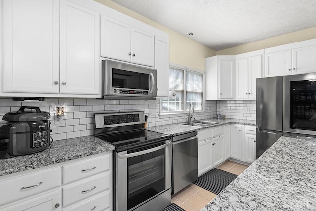 4710 Hummingbird Ln, Concord, VA 24538 - kitchen with appliances with stainless steel finishes, a sink, light tile patterned floors, white cabinetry, and light stone countertops