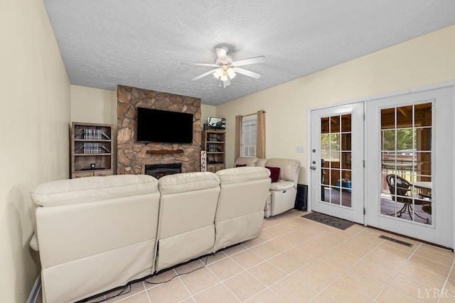 4710 Hummingbird Ln, Concord, VA 24538 - living area with ceiling fan, a textured ceiling, a stone fireplace, and light tile patterned flooring