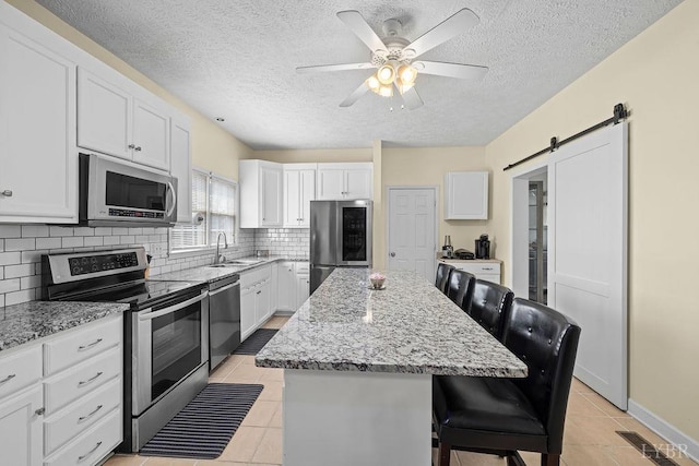 4710 Hummingbird Ln, Concord, VA 24538 - kitchen with appliances with stainless steel finishes, a sink, light tile patterned flooring, a center island, and a breakfast bar