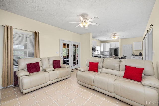 4710 Hummingbird Ln, Concord, VA 24538 - living room with ceiling fan, a textured ceiling, light tile patterned floors, a barn door, and french doors