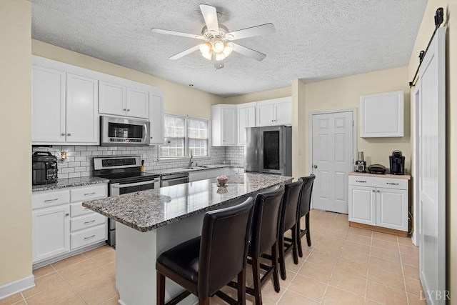 4710 Hummingbird Ln, Concord, VA 24538 - kitchen with stainless steel appliances, a kitchen bar, white cabinets, backsplash, and a textured ceiling