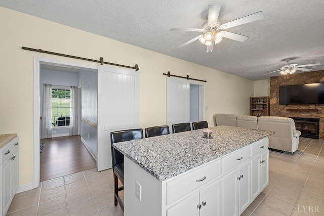 4710 Hummingbird Ln, Concord, VA 24538 - kitchen with a barn door, a ceiling fan, a textured ceiling, light tile patterned floors, and white cabinetry
