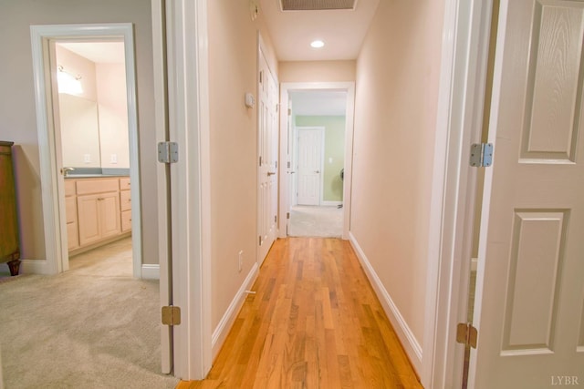 corridor featuring baseboards and light wood-style flooring