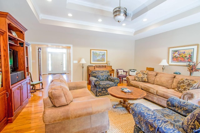 living room featuring light wood-type flooring, crown molding, recessed lighting, and a raised ceiling