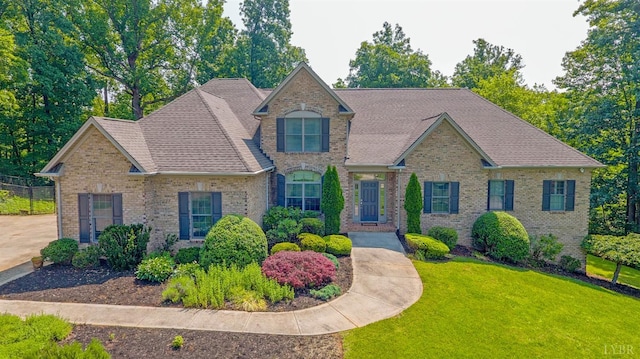 traditional-style home featuring a front yard, brick siding, and a shingled roof