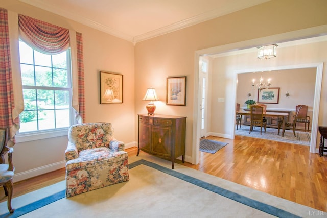 sitting room with crown molding, a chandelier, wood finished floors, and healthy amount of natural light