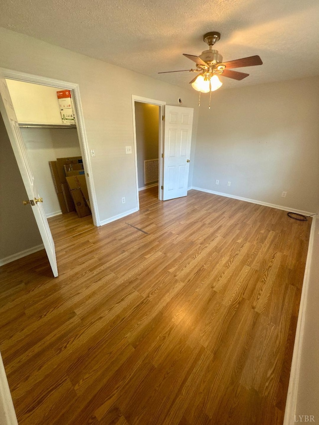 511 Bent Oak Ct, Lynchburg, VA 24502 - unfurnished bedroom with wood finished floors, a walk in closet, a textured ceiling, ceiling fan, and a closet