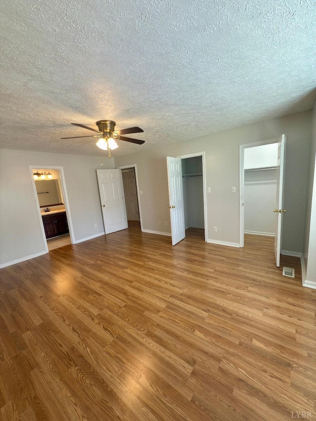 511 Bent Oak Ct, Lynchburg, VA 24502 - unfurnished bedroom with a textured ceiling, wood finished floors, ceiling fan, ensuite bathroom, and two closets